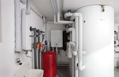 Wandhängende Inneneinheit der Wärmepumpe (weiß), daneben die Frischwasserstation (schwarz, halb verdeckt) und vorne der 1000-Liter-Wärmepumpen-Solarspeicher. (Foto: Junkers)