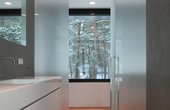 Hochwertige Bäder – in jedem Detail. Vom Elternbad gelangt die Familie auf die Dachterrasse. Die angrenzende Sauna ermöglicht durch ein raumgreifendes Fenster Ausblick auf die umliegenden Bäume. (Foto: nieberg architect)