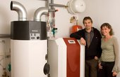 Familie Kossack neben der Sole/Wasser und Warmwasser-Wärmepumpe im Heizungskeller (Foto: Glen Dimplex, Kulmbach)