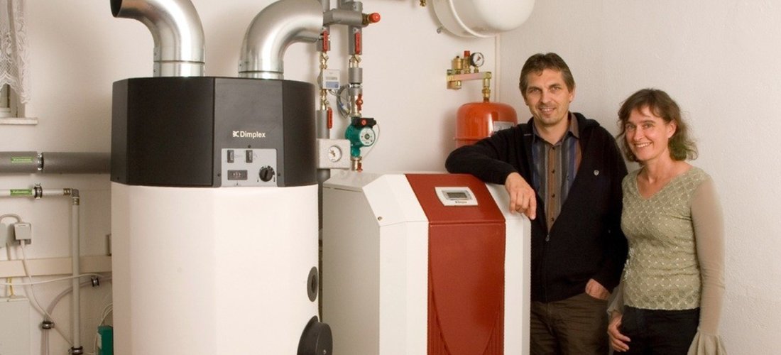 Familie Kossack neben der Sole/Wasser und Warmwasser-Wärmepumpe im Heizungskeller (Foto: Glen Dimplex, Kulmbach)