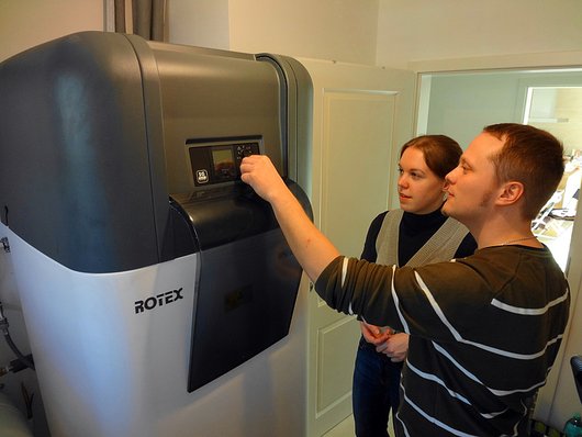 Die Bauherren Sara Pietsch und Sebastian Kerkojus vor der Platz sparenden Inneneinheit der 6-kW-Luft-Wasser-Wärmepumpe, in die der 500 Liter fassende Hygienespeicher integriert ist. Foto: Rotex Kompakte Wärmepumpenheizung braucht weniger als 1 m2 Platz im Hauswirtschaftsraum Foto: Rotex